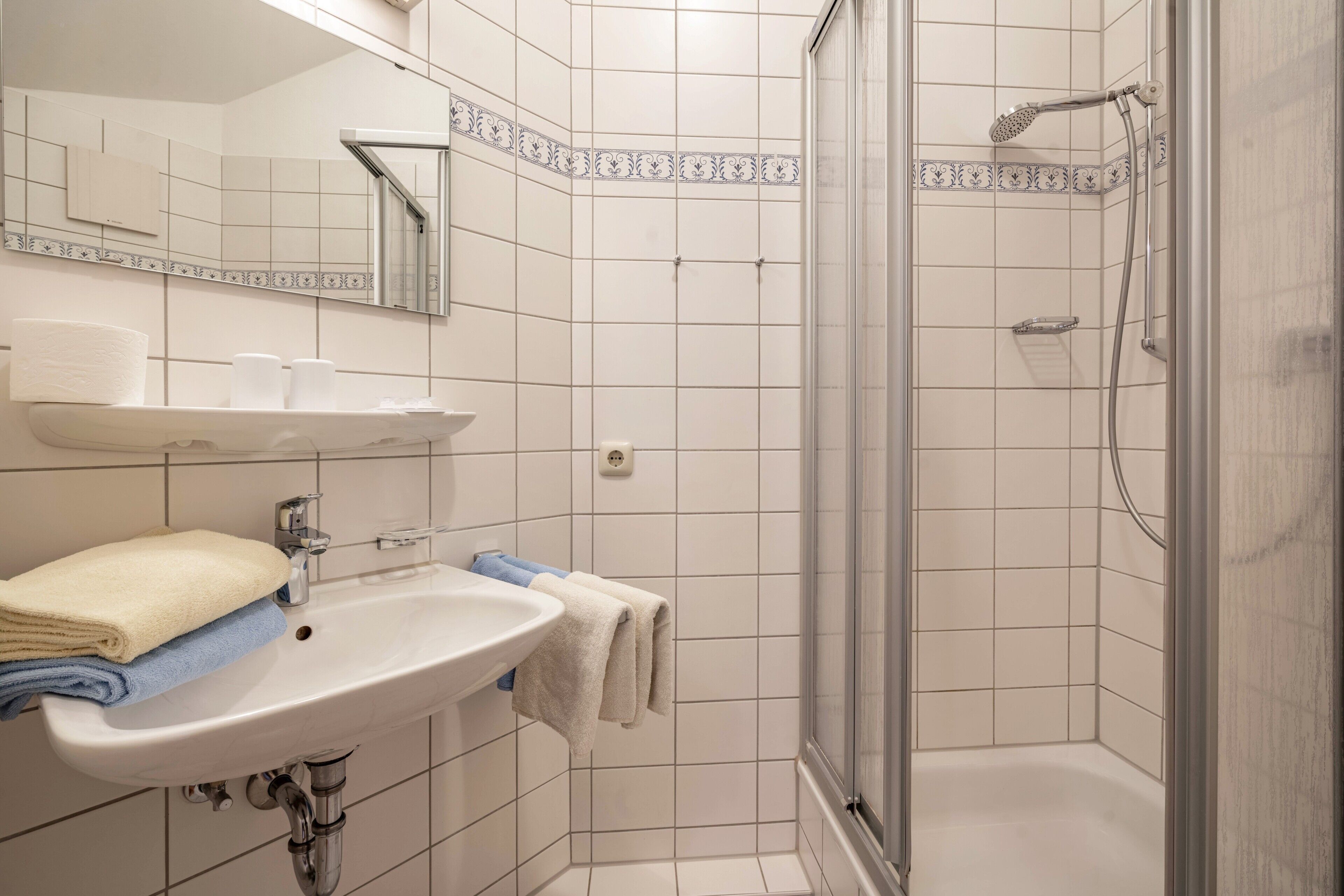 Une salle de bain avec un lavabo, un miroir et une douche.