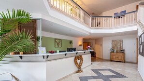 A reception area with a counter, potted plants, a heart-shaped decoration, and a staircase.