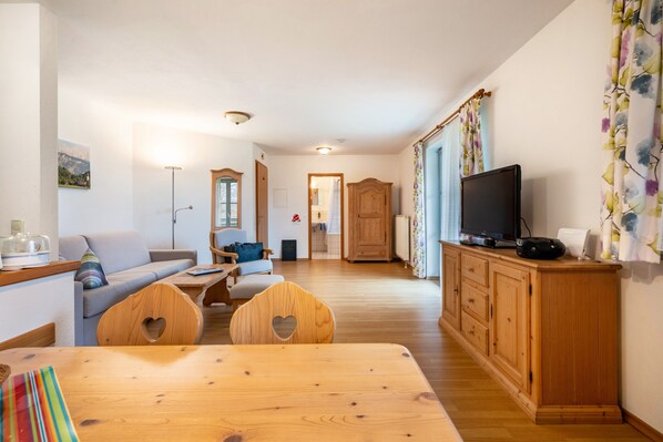 Un salon chaleureux avec une table à manger en bois, des chaises en forme de cœur, un téléviseur et un meuble.