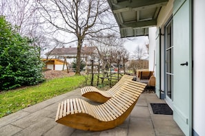 A curved wooden bench outside a building with a door and windows.
