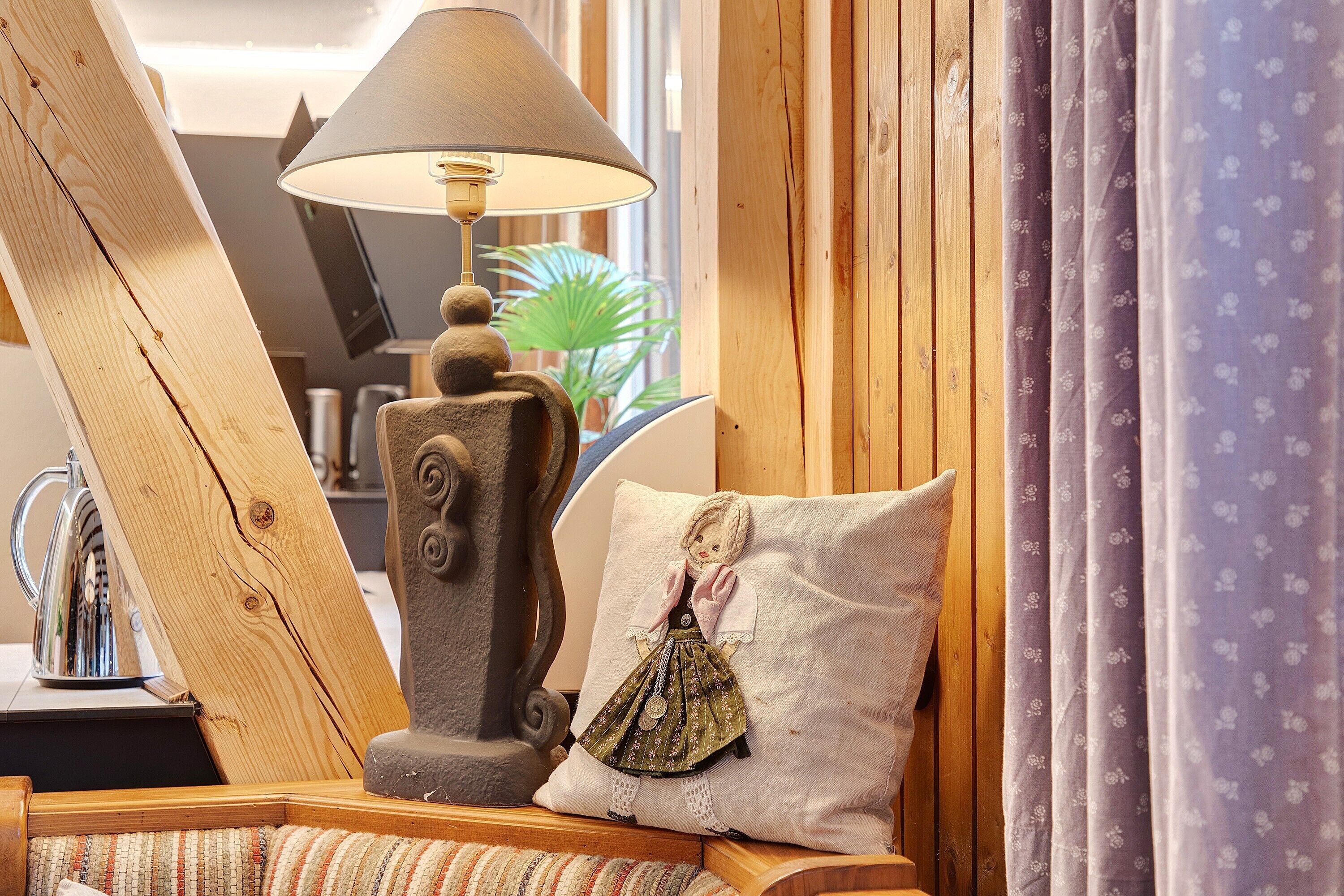 A wooden-framed room with a lamp, a decorative pillow, and a plant.