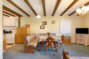 Una habitación acogedora con un banco de madera, una mesa de comedor y un televisor.