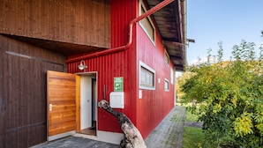 En röd byggnad med en trädörr, en skylt och ett rör som löper längs sidan.