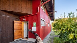 A red building with a wooden door, a sign, and a pipe running along the side. - Apartment '3' with Shared Garden and Wi-Fi (Hayingen-Indelhausen)