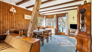 A wooden interior with a dining table, benches, a cabinet, and a television. - Apartment '3' with Shared Garden and Wi-Fi (Hayingen-Indelhausen)