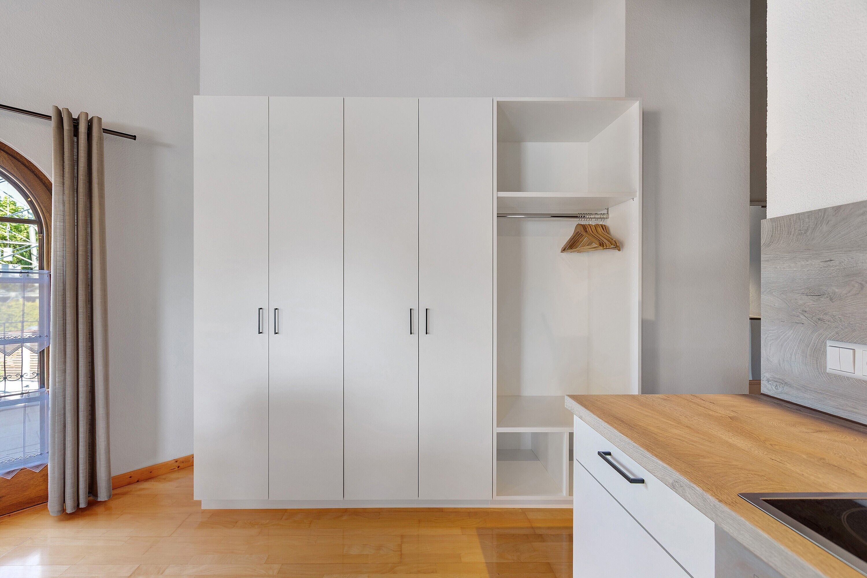 Une cuisine moderne avec des meubles blancs, un plan de travail en bois et une cuisinière intégrée.