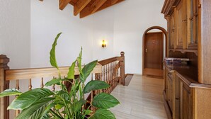 Una escalera de madera con barandilla, una puerta de madera y un aplique de pared.