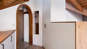 Un pasillo con vigas de madera, paredes blancas y una puerta de madera.