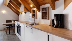 Una cocina con vigas de madera, estufa, lavaplatos y cafetera.