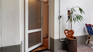 A doorway leading to a room with a sliding door, a potted plant, and a wall-mounted light fixture. - Apartment 'Zapf' with Shared Terrace, Shared Garden and Wi-Fi (Forbach)