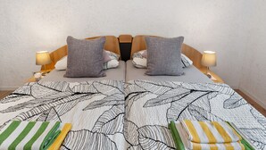 A bed with a leaf-patterned bedspread, two pillows, and two bedside lamps. - Apartment 'Zapf' with Shared Terrace, Shared Garden and Wi-Fi (Forbach)