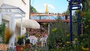 A garden with a table and chairs, a thatched umbrella, and a stone wall. - Apartment 'Mengeler' with Private Terrace, Private Garden and Wi-Fi (Freiburg im Breisgau)
