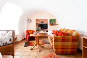 Un salon confortable avec un canapé, un fauteuil et un téléviseur.