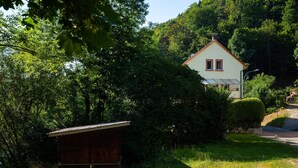 A house with a red roof, surrounded by dense greenery and a small wooden structure. - Apartment 'Mengeler' with Private Terrace, Private Garden and Wi-Fi (Freiburg im Breisgau)