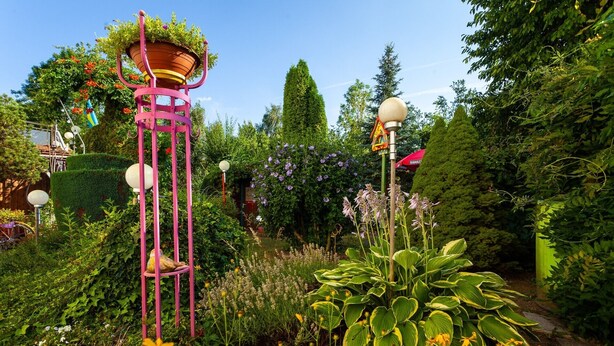 A garden with a tall pink structure, various plants, and a lamp post. - Apartment 'Mengeler' with Private Terrace, Private Garden and Wi-Fi (Freiburg im Breisgau)