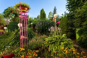 A garden with a tall pink structure, various plants, and a lamp post.