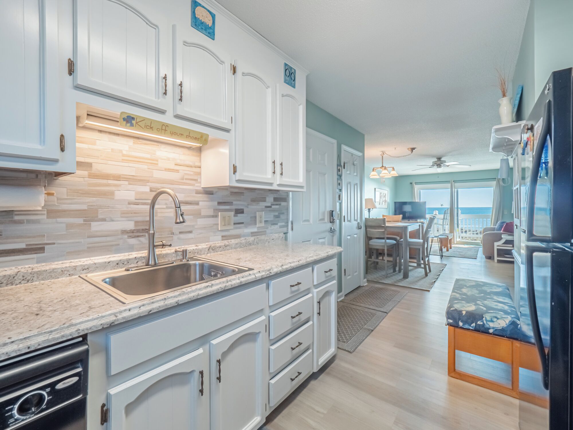 A modern kitchen with white cabinets, a granite countertop, and a stainless steel sink.