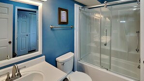 A bathroom with a white sink, toilet, and glass-enclosed shower. - Pelican Nest by Topsail Realty (Sneads Ferry)
