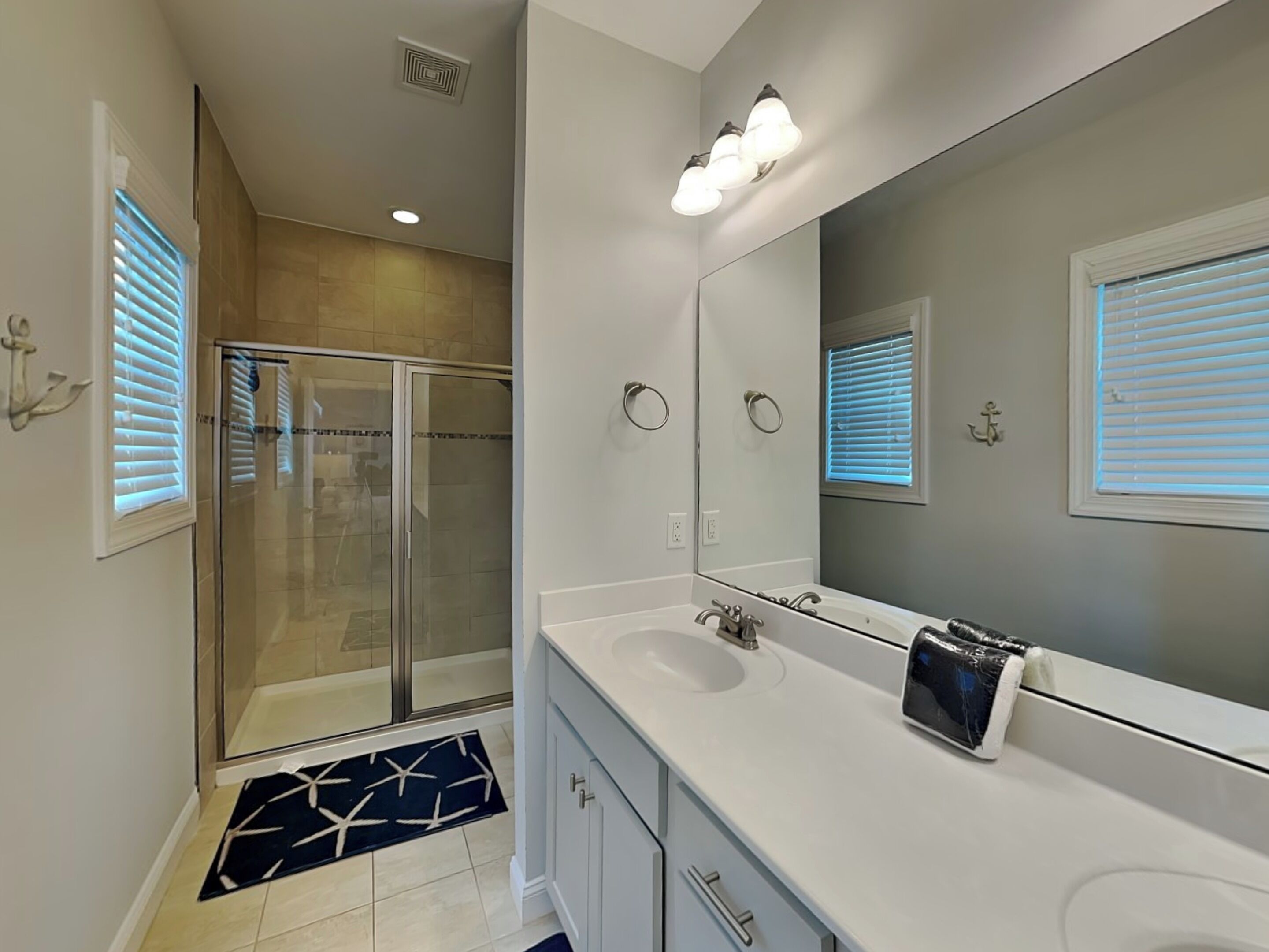 A modern bathroom with a glass shower enclosure, a large mirror, and a white vanity with a sink.