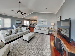 A modern living room with a sofa, ottoman, and entertainment unit. - Queens Grant by Topsail Realty (Holly Ridge)