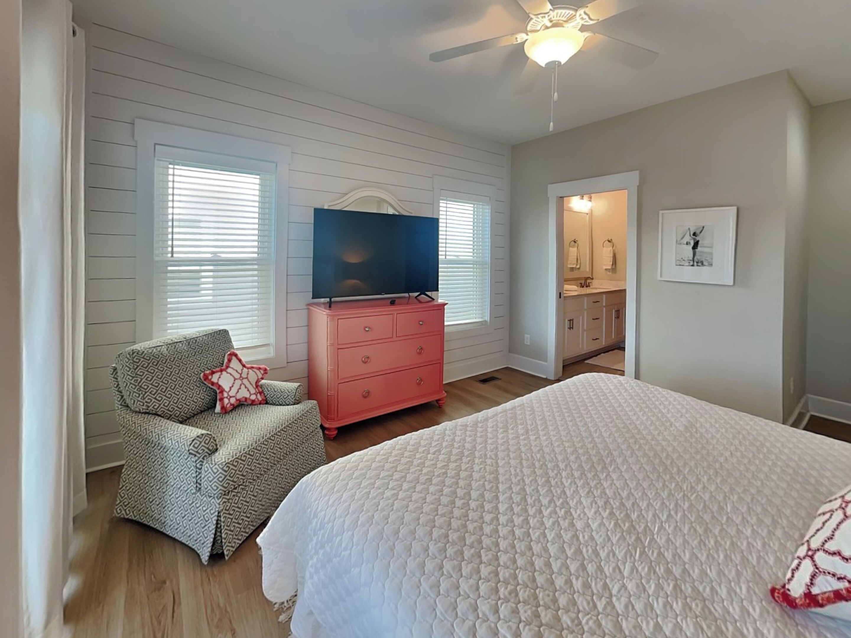 Un dormitorio con cama, cómoda, televisor y una silla.
