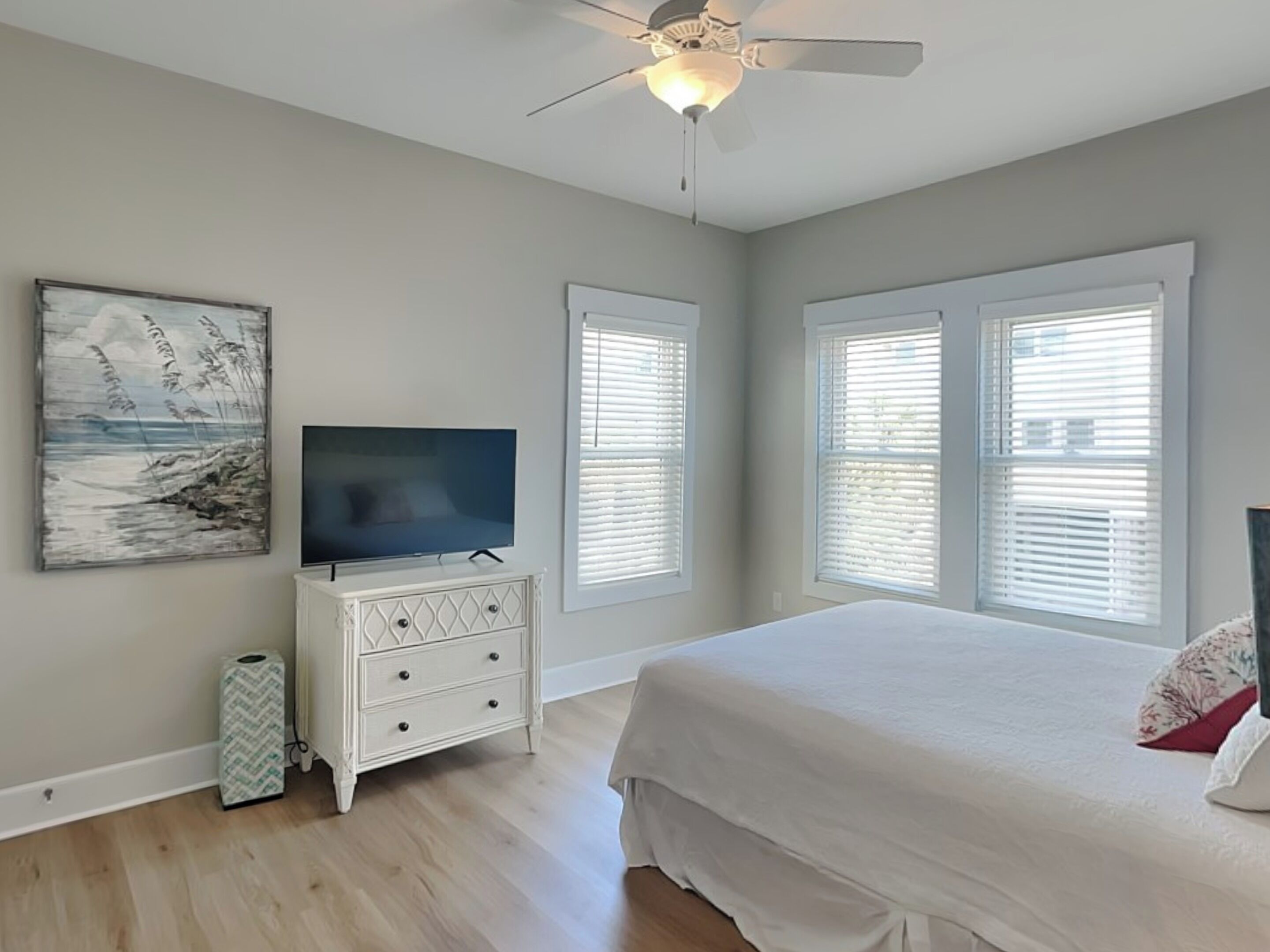 A bedroom with a bed, a TV on a dresser, and a ceiling fan.