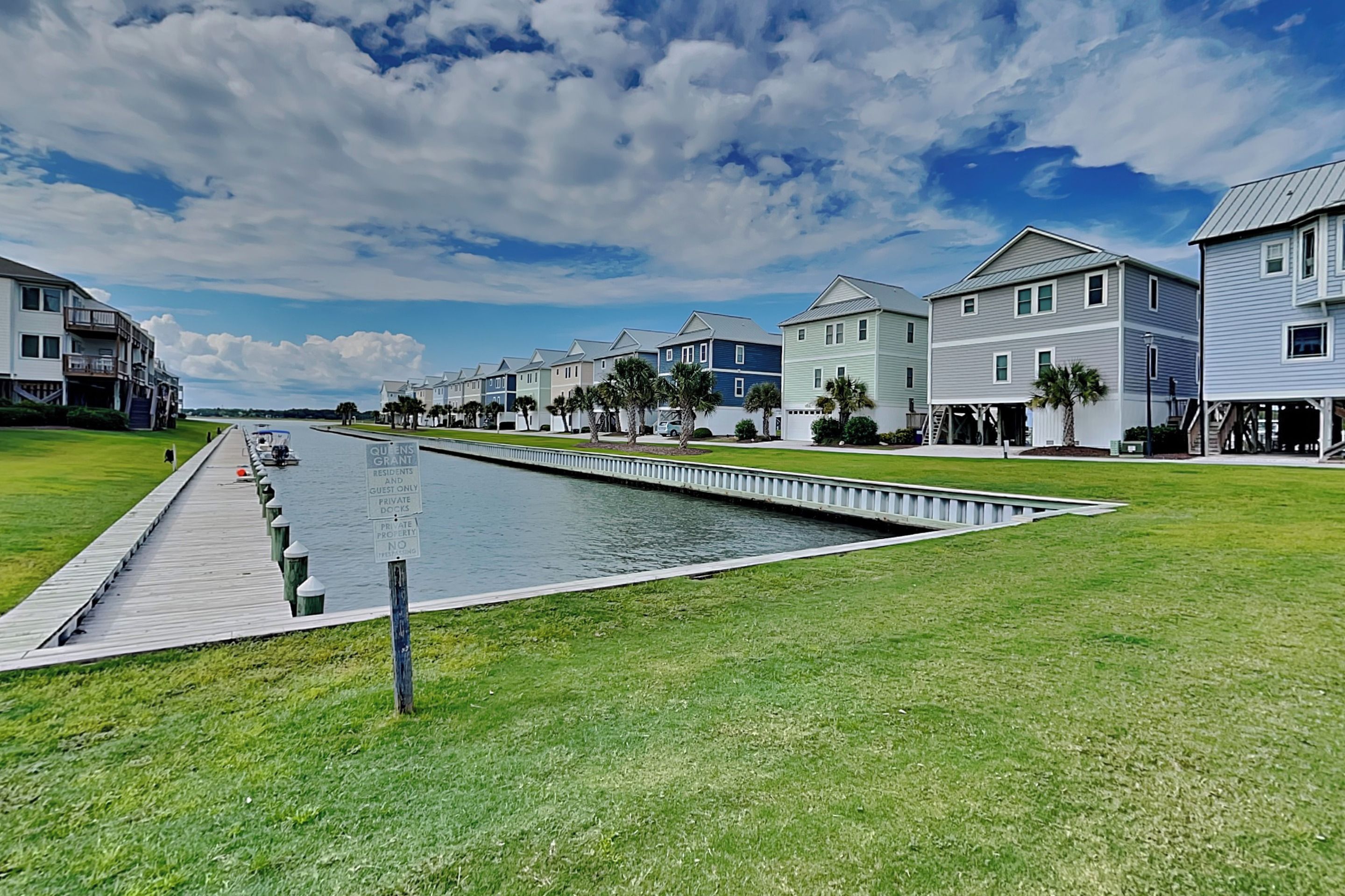 A waterfront property with a long dock, a narrow waterway, and a row of colorful houses.