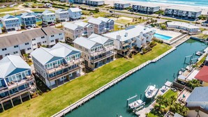 Un quartier résidentiel en bord de mer, avec des maisons modernes, une marina et une plage en arrière-plan.