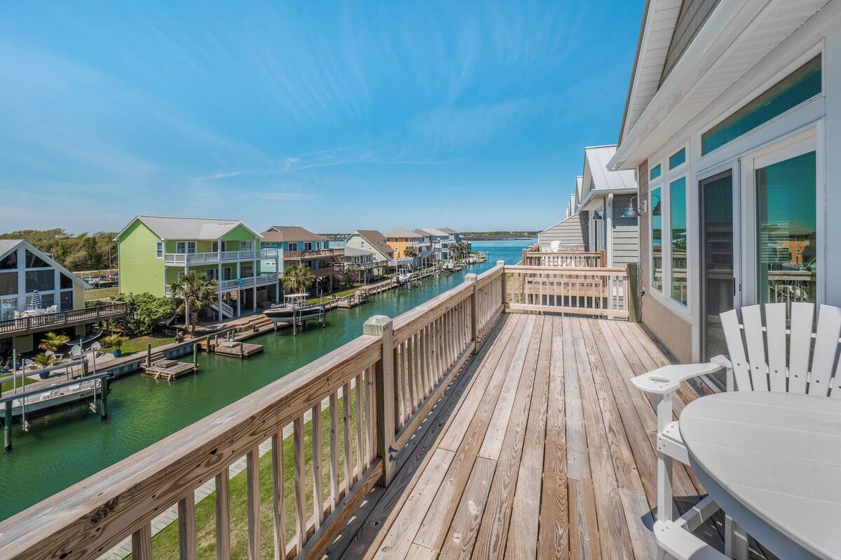 A wooden deck with a view of a marina and houses.