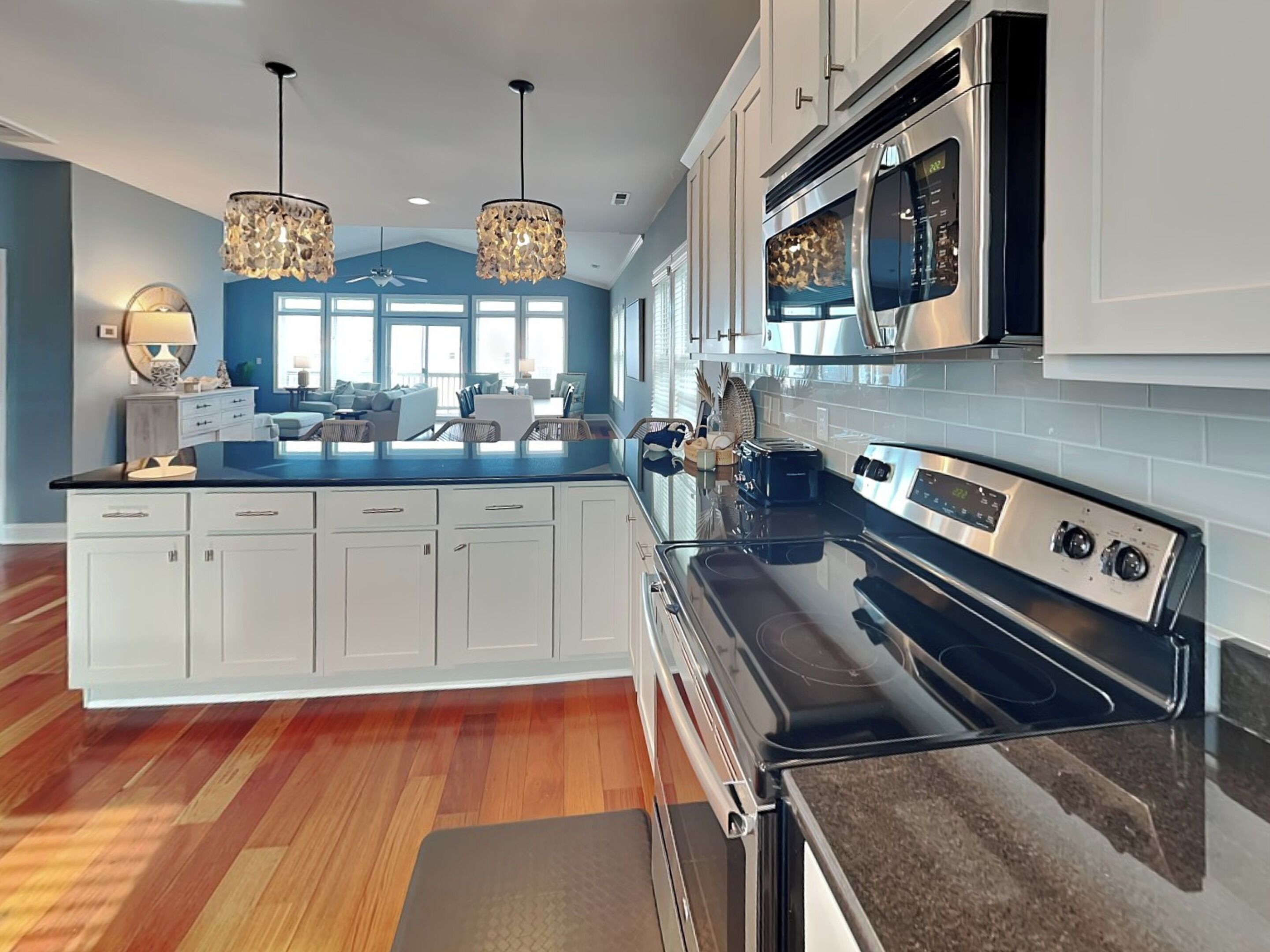 A modern kitchen with white cabinets, a black stove, and a large island with a sink.