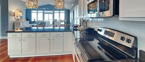 A modern kitchen with white cabinets, a black stove, and a large island with a sink.