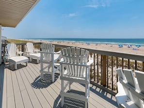 A deck with Adirondack chairs overlooking a beach with umbrellas. - Queens Grant by Topsail Realty (Holly Ridge)