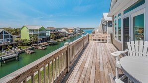 Une terrasse en bois offrant une vue sur un port de plaisance et des maisons.