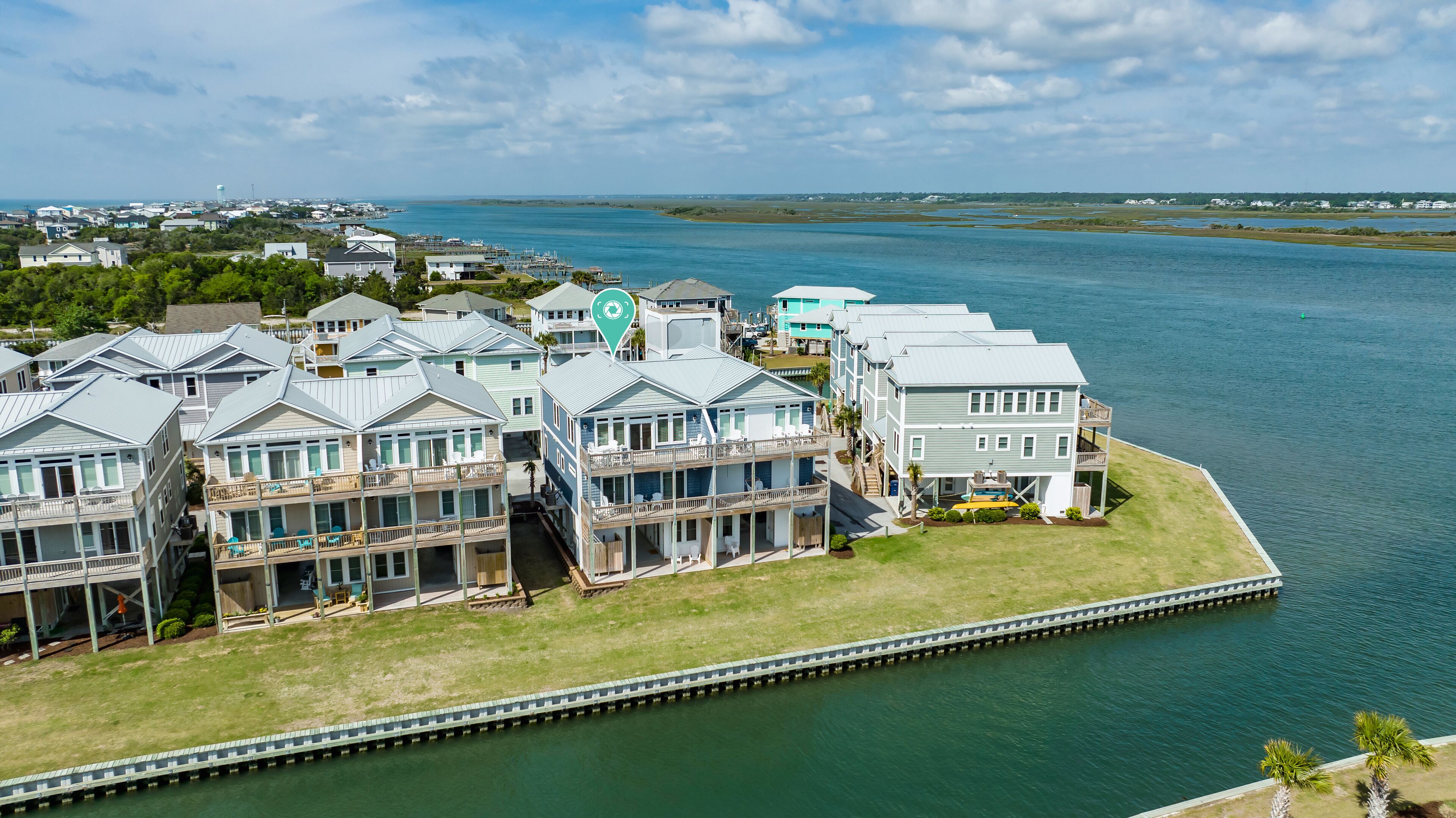 A coastal hotel with multiple balconies, a dock, and a view of the water.
