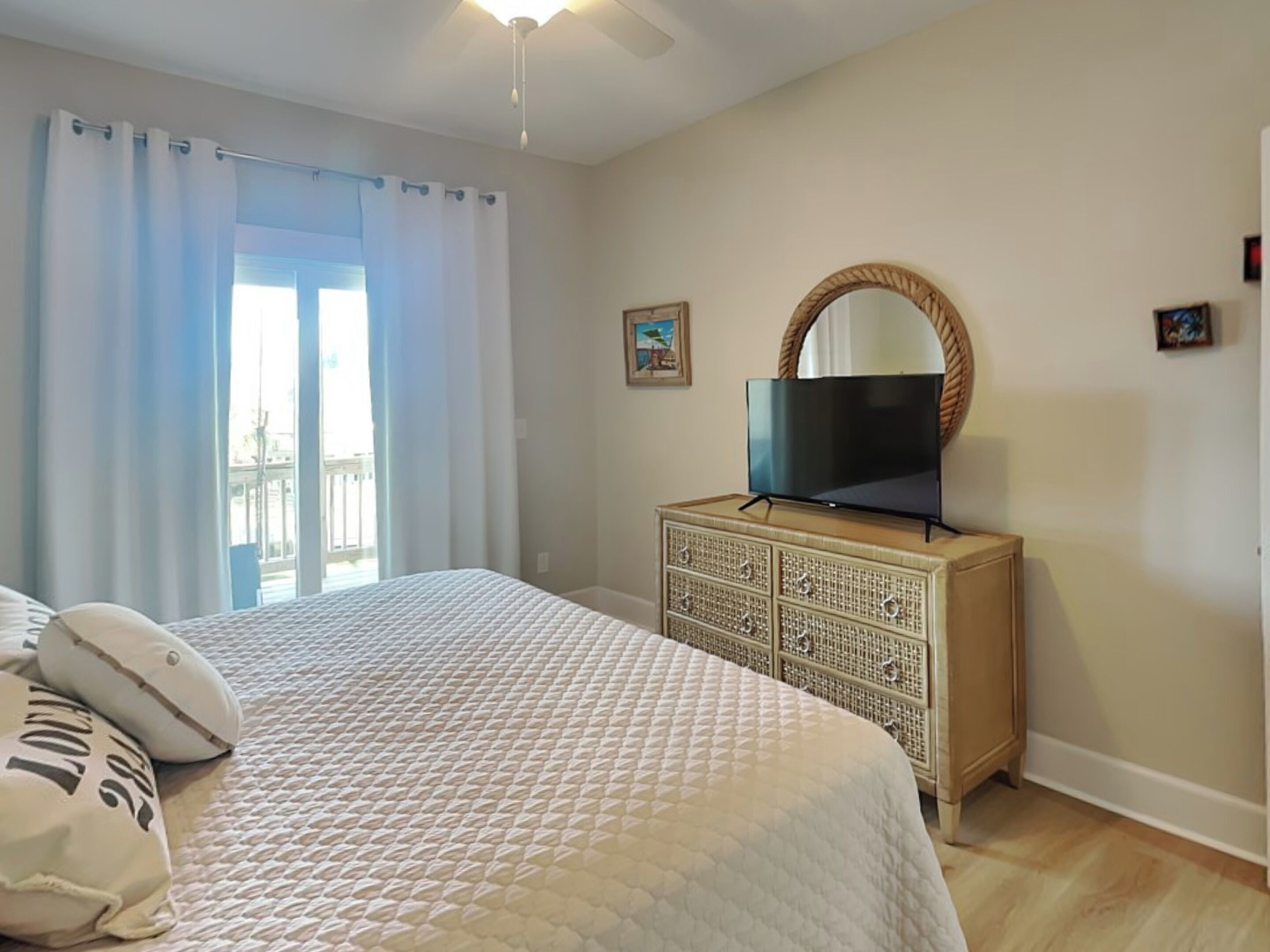 A bedroom with a bed, a dresser, a television, and a window with curtains.
