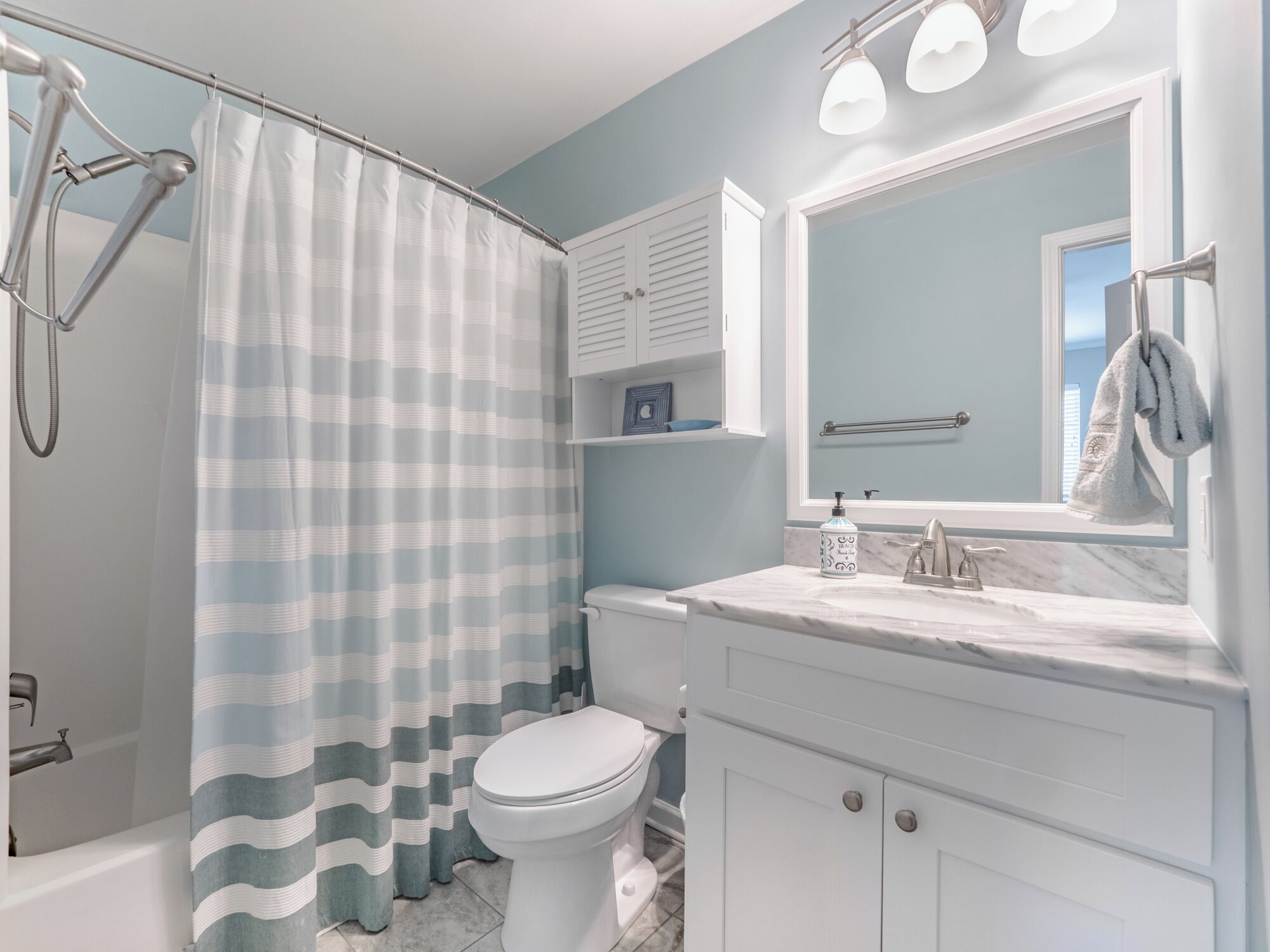 A bathroom with a shower curtain, toilet, sink, and vanity.