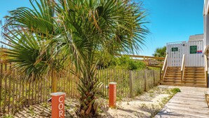 A wooden boardwalk leading to a building with a sign that reads "CORAL". - Coral Surf #A1 - Beachy Keen by Carolina Retreats (Carolina Beach)
