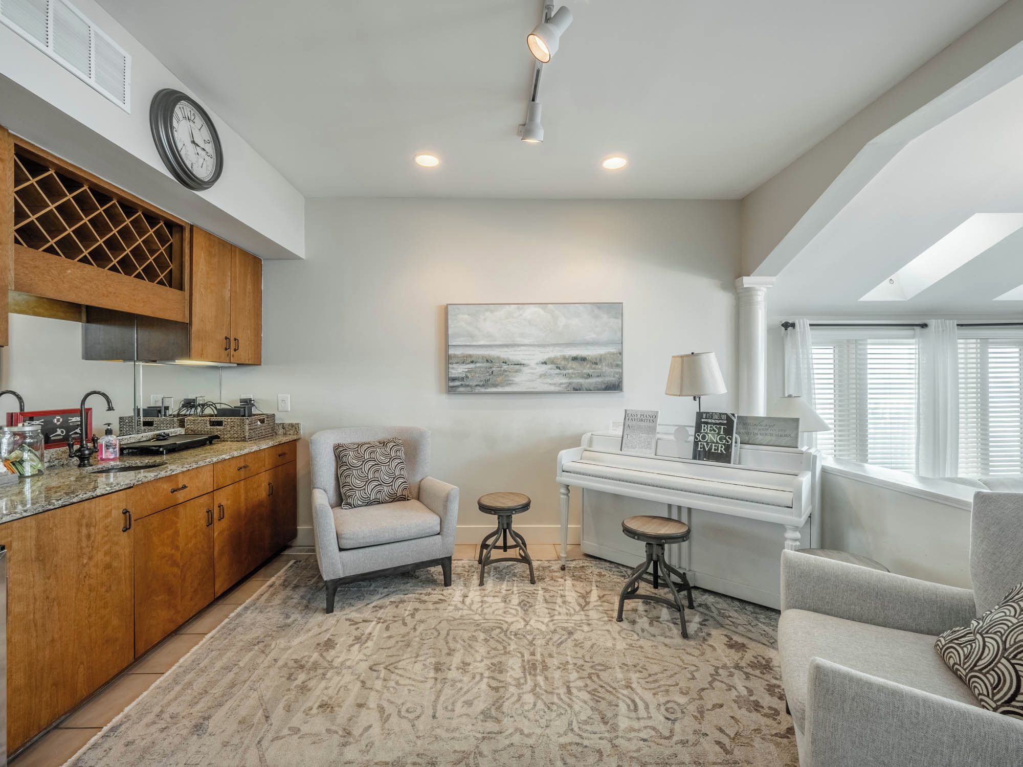 A modern kitchen with wooden cabinets, a built-in wine rack, a dining area with a piano, and a cozy seating arrangement.