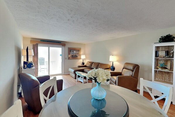 A living room with a dining table, white chairs, a sofa, and a coffee table.