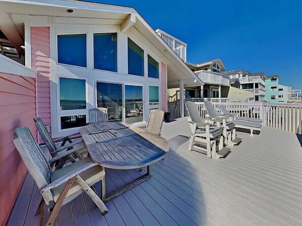 A deck with a table and chairs, overlooking a beach. - Ocean Dunes by Carolina Retreats (Kure Beach)