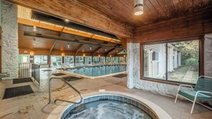 A spa area with a hot tub, wooden ceiling, stone walls, and a view of a house. - Ocean Dunes by Carolina Retreats (Kure Beach)