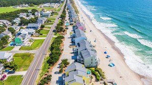 A coastal residential area with houses along the beach, a road, and ocean views. - Ocean Dunes by Carolina Retreats (Kure Beach)