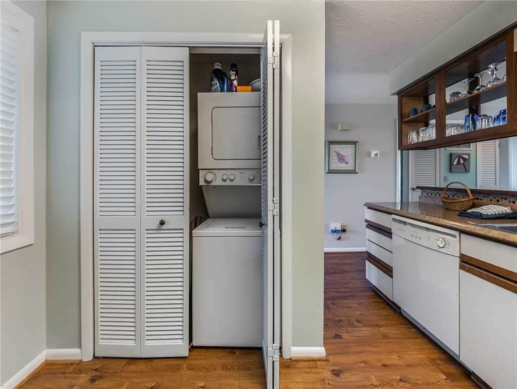 A laundry room with a washer and dryer, a wooden cabinet with dishes, and a white door.