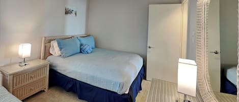 Une chambre à coucher avec un lit, des tables de chevet, un miroir et une porte.