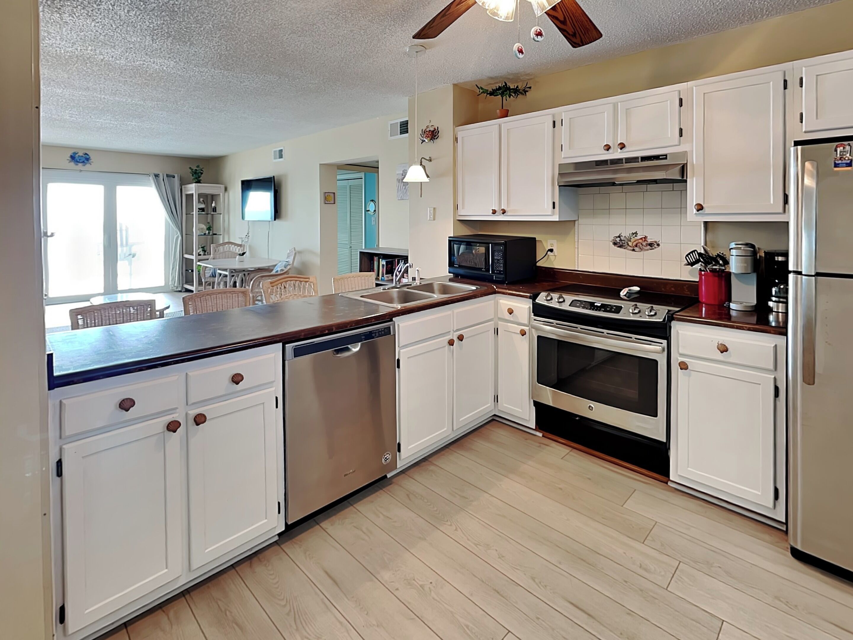 A modern kitchen with white cabinets, stainless steel appliances, and a wooden countertop.