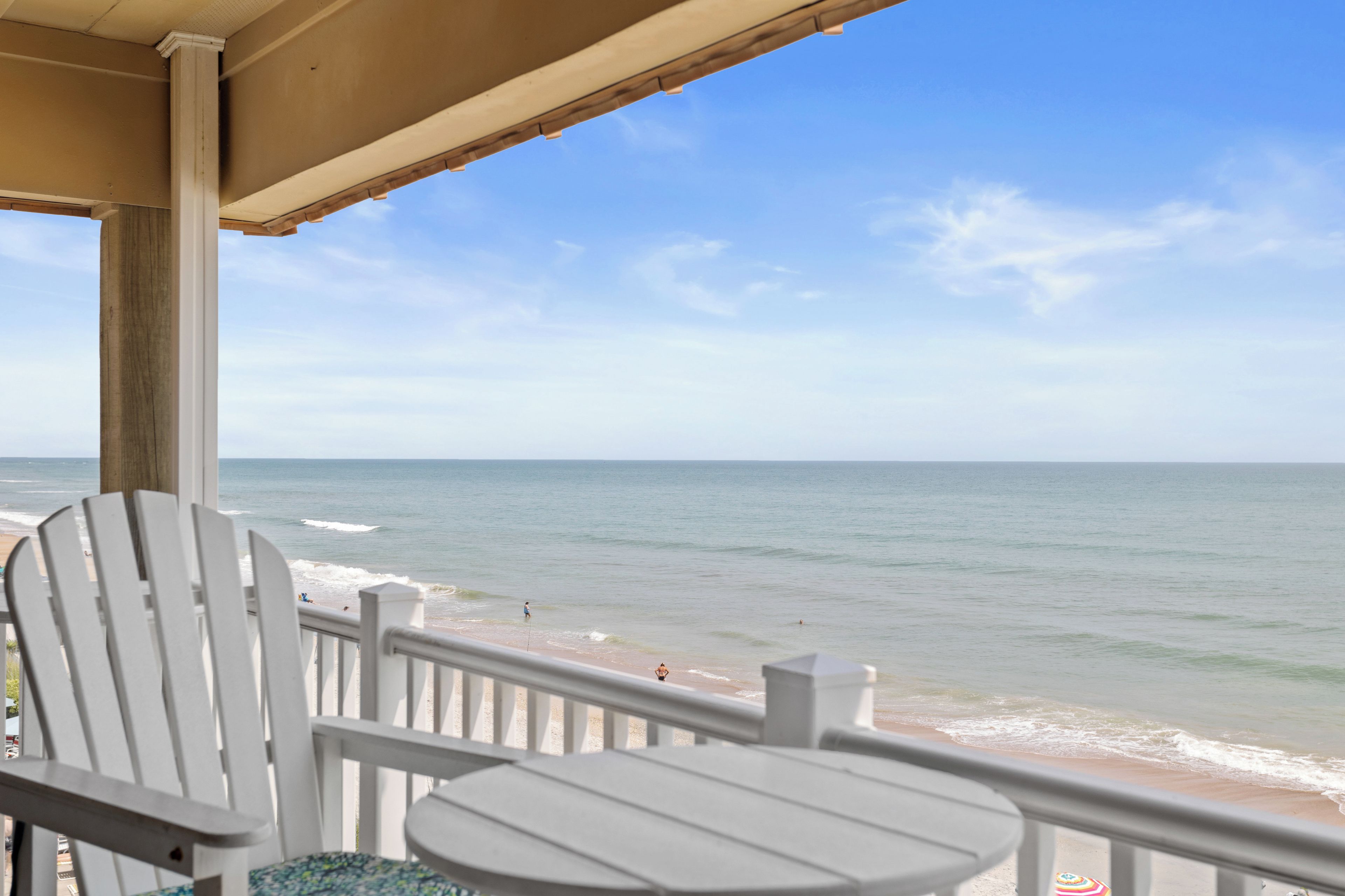 Ein Balkon mit Meerblick, ausgestattet mit einem weißen Stuhl und einem kleinen Tisch.