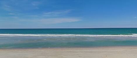 A beach with sand and ocean waves.
