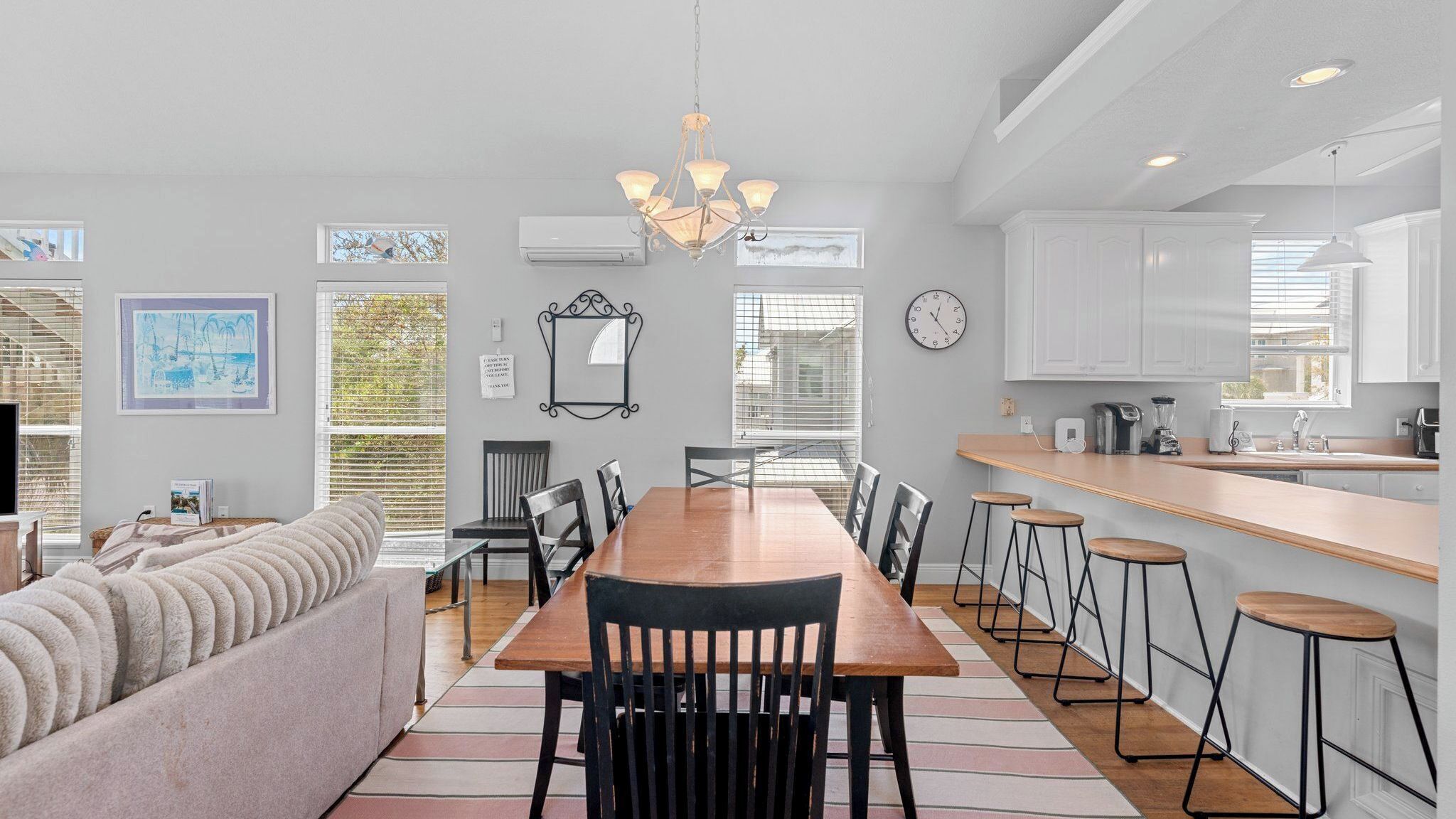 A modern kitchen with white cabinets, a wooden dining table, and bar stools.