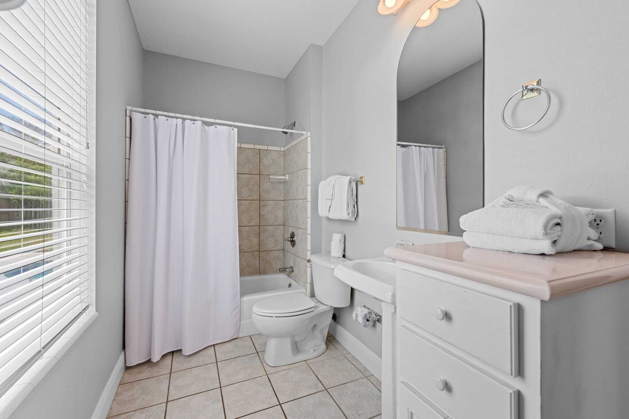 Une salle de bain équipée d’une douche, de toilettes, d’un lavabo et d’un miroir.