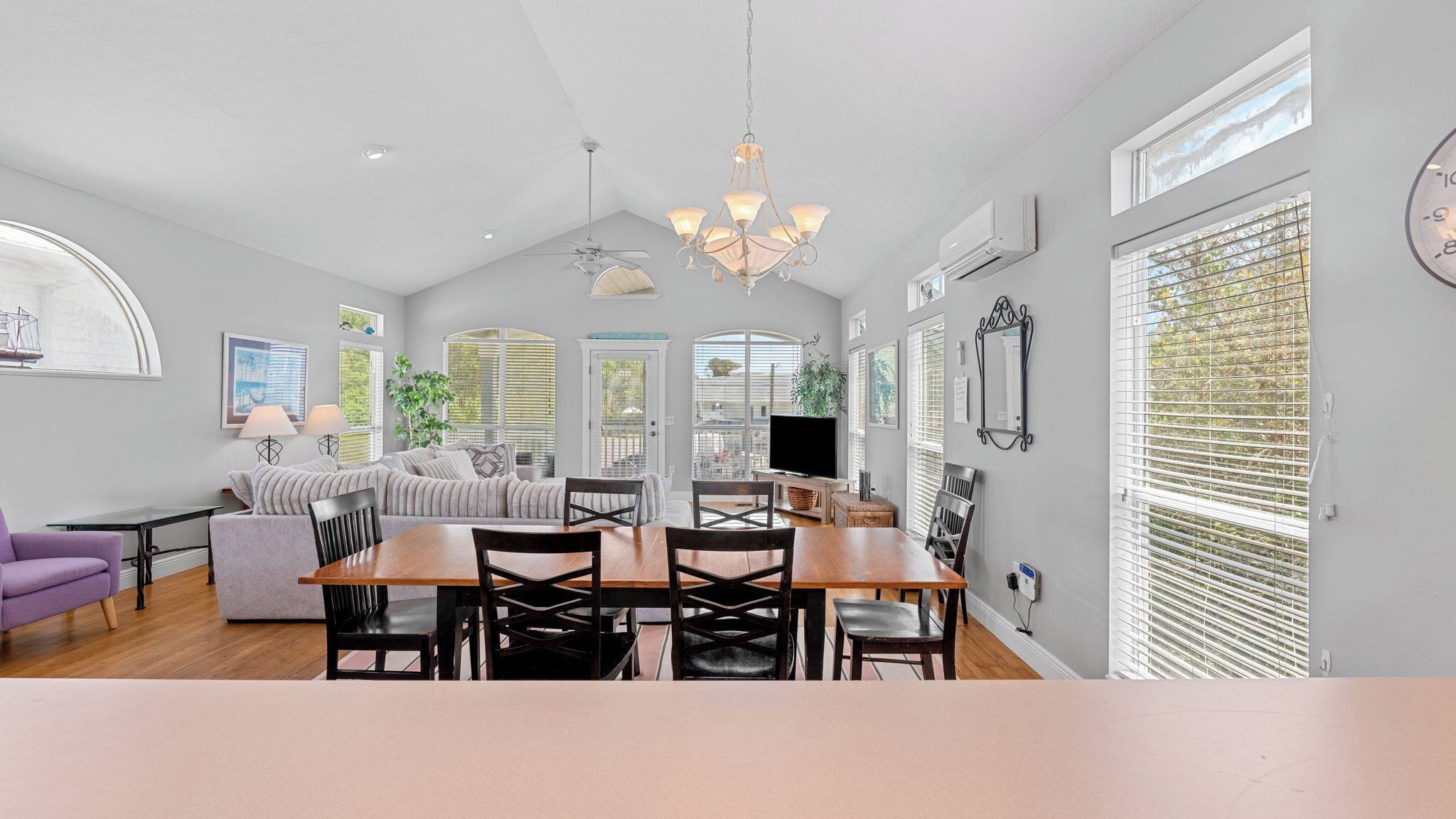 A spacious living area with a dining table, sofas, and a chandelier.